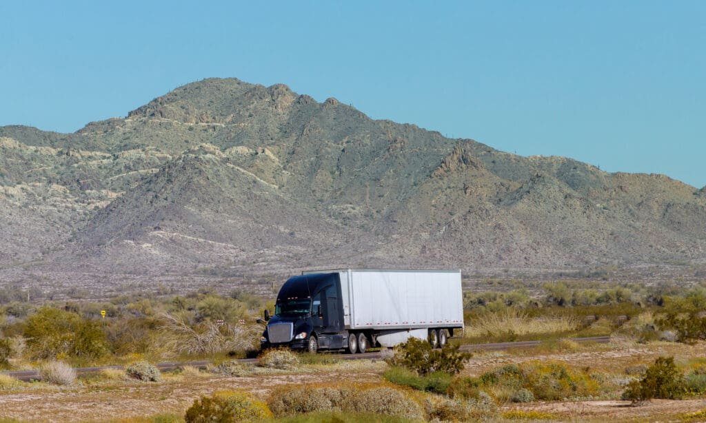 black truck with white trailer attached going down the road