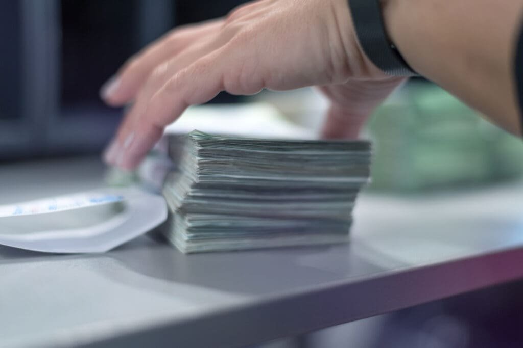 Bank employees sorting and counting money inside bank vault.